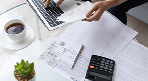 woman sorting through bills and receipts next to a laptop